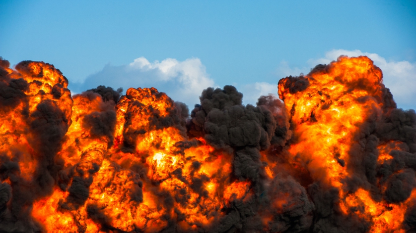 Intense explosion with fire and black smoke and sky in the background